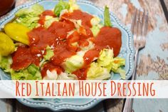 a blue plate topped with lettuce and red italian house dressing next to a fork