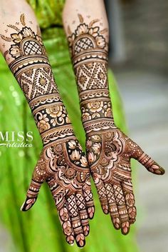 two hands with henna tattoos on them, one is showing off the intricate design