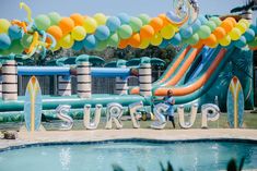 an inflatable pool with balloons and the word surf up on it