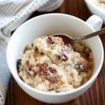 two white bowls filled with oatmeal and raisins on a wooden table