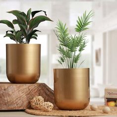 two gold planters sitting on top of a wooden table