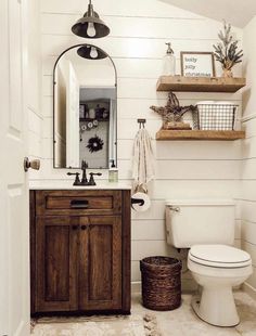 a white toilet sitting next to a wooden sink vanity in a bathroom under a mirror