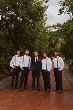 a group of men standing next to each other in front of trees and dirt ground