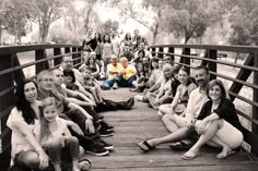 a group of people are sitting on a bridge and posing for a photo with the photographer