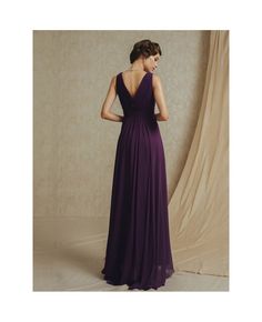 a woman in a long purple dress looking back at the camera with her hand on her hip