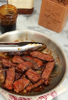 there is meat in the pan on the table next to some bottles and sauces