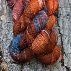 three skeins of yarn sitting on top of a tree trunk