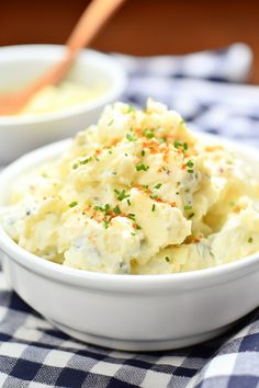 a white bowl filled with mashed potatoes on top of a checkered table cloth