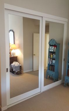 a bedroom with mirrored closet doors and a blue bookcase in the corner on the floor