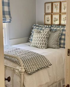 a bed with blue and white comforters in a bedroom next to pictures on the wall