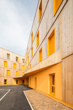 an empty parking lot in front of a building with yellow shutters on the windows