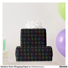 a three tiered black cake with multicolored stars on it