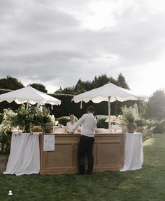 a man and woman standing next to each other at a table with white umbrellas