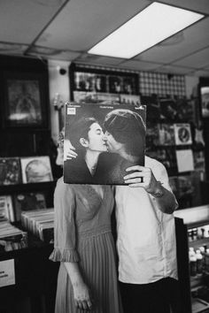 a man and woman kissing in front of a record store with records on the shelves