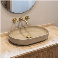 a bathroom sink sitting under a round mirror on top of a wooden counter next to a wall mounted faucet