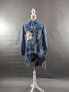 a blue jean jacket on a white mannequin stand with a gray wall in the background