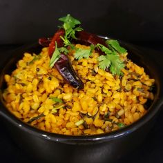 a bowl filled with rice and vegetables on top of a black tablecloth covered table