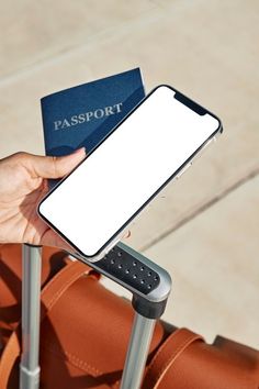 a person holding a passport and a cell phone in their hand while sitting on a chair