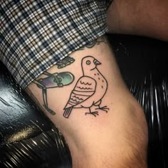 a small bird tattoo on the left arm and leg, with a man's foot in the background