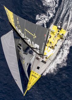 an aerial view of a sailboat in the middle of the ocean with its sails down