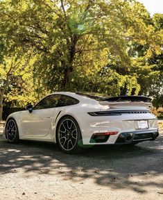 a white porsche sports car parked in front of some trees