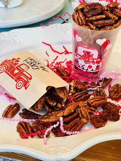 pecans are on a plate next to a paper bag and some pink confetti