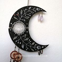 a black and white moon with beads hanging from it's side on a wall