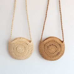 two handmade purses hanging from chains on the wall, one is made out of straw