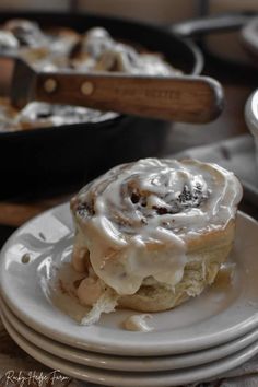 a cinnamon roll sitting on top of a white plate next to other plates and pans