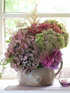 a vase filled with lots of purple and green flowers