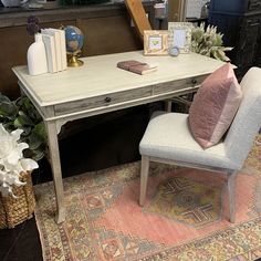 a desk with a chair and books on top of it next to a rug in front of a fireplace