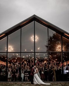 a bride and groom standing in front of a large group of people holding sparklers