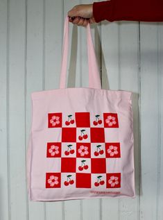 Pack up a picnic in this vibrant pink tote bag, displaying a checkerboard of cherries and cherry blossoms. It's the perfect accessory for spring! Totes are made of 12 oz cotton with self-fabric handles. They're very sturdy, you don't have to worry about overloading or ripping these. They measure a solid 10 inches wide by 13 1/2 inches high and expand to about 5 inches deep. Machine washable, tumble dry, iron as needed, bleach not recommended. Picnic Tote, Pink Tote Bag, Pink Tote Bags, Pack Up, Pink Tote, Foodie Gifts, A Picnic, Kids Hats, Food Gifts