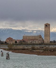 a large tower with a clock on the side of it next to a body of water