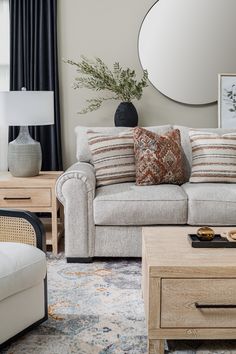 a living room filled with furniture and a round mirror on the wall above it's headboard