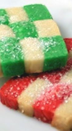 two cookies with green and red frosting on them sitting on a white plate next to each other