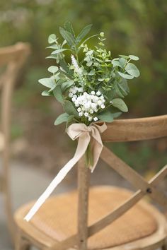 a bouquet of flowers tied to the back of a wooden chair