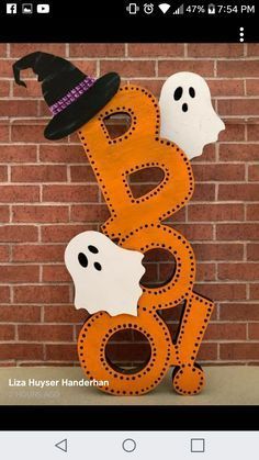 a wooden sign that says boo and three ghost faces with a black hat on top