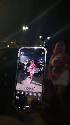 a person holding up a cell phone to take a selfie with a car in the background