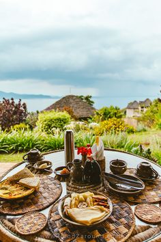 an outdoor table with plates and cups on it