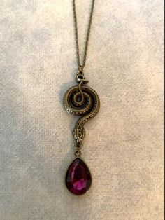 "Nicely detailed bronze tone entwined snake necklace with hanging purple stone. Pendant measures 2 7/8\" L X 1\" W and is on an 18\" chain. ★ Want to see more? Please visit my shop at: https://www.etsy.com/shop/DesignsByPeg" Snake Pendant Necklace, Snake Themed Jewelry, Black Snake-shaped Necklaces As Gift, Bronze Snake-shaped Jewelry Gift, Emerald Green Jewelry, Serpent Necklace, Unique Metal Snake-shaped Necklace, Serpent Jewelry, Necklace Snake