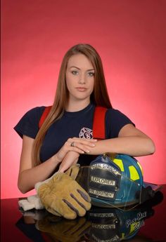 a young woman holding a hard hat and glove in front of a red background,