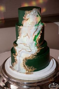 a green and gold wedding cake on a silver platter