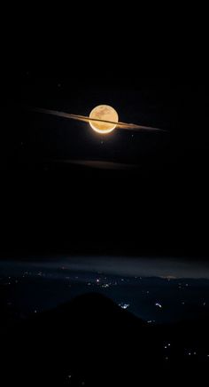 the moon is shining brightly in the dark night sky over a mountain range and city lights