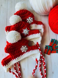 knitted christmas hats and balls of yarn on a white wooden floor with red and white decorations