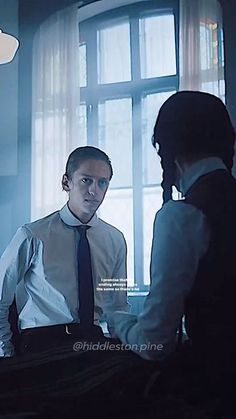 a man in a tie standing next to a woman at a desk with a computer