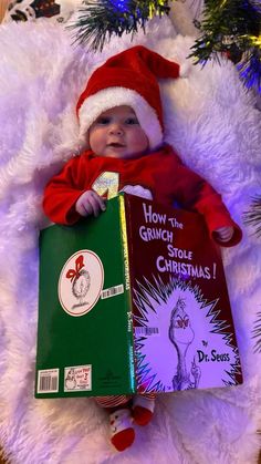 a baby wearing a santa hat and holding a book