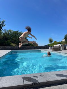 a person jumping into a swimming pool in the middle of a sunny day with no one around