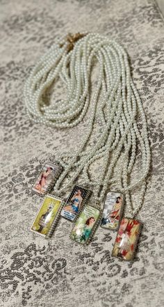 a white necklace with pictures on it and some pearls hanging from the end of it