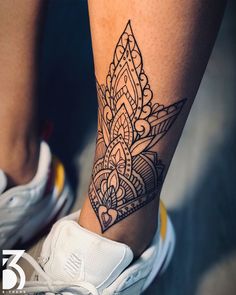 a close up of a person's foot with a tattoo design on the leg